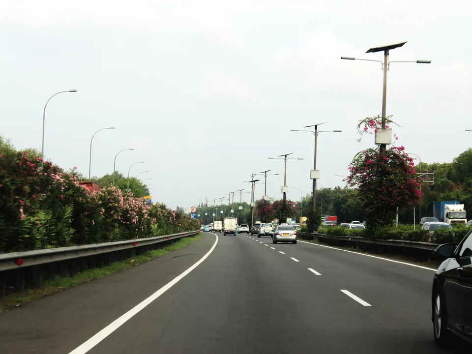 Jalan arteri empat lajur dengan lampu penerangan dan pagar pengaman
